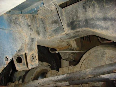 1972 Land Rover Land Rover - Close-up view of the rusty undercarriage and suspension of a vehicle, with a tire visible in the background.
