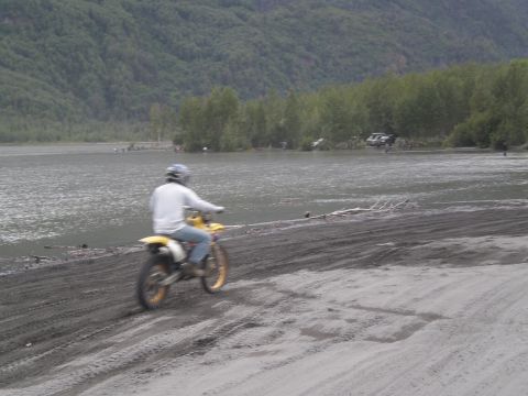 1987 Suzuki Samurai - Rider on a dirt bike navigates sandy terrain next to a body of water.
