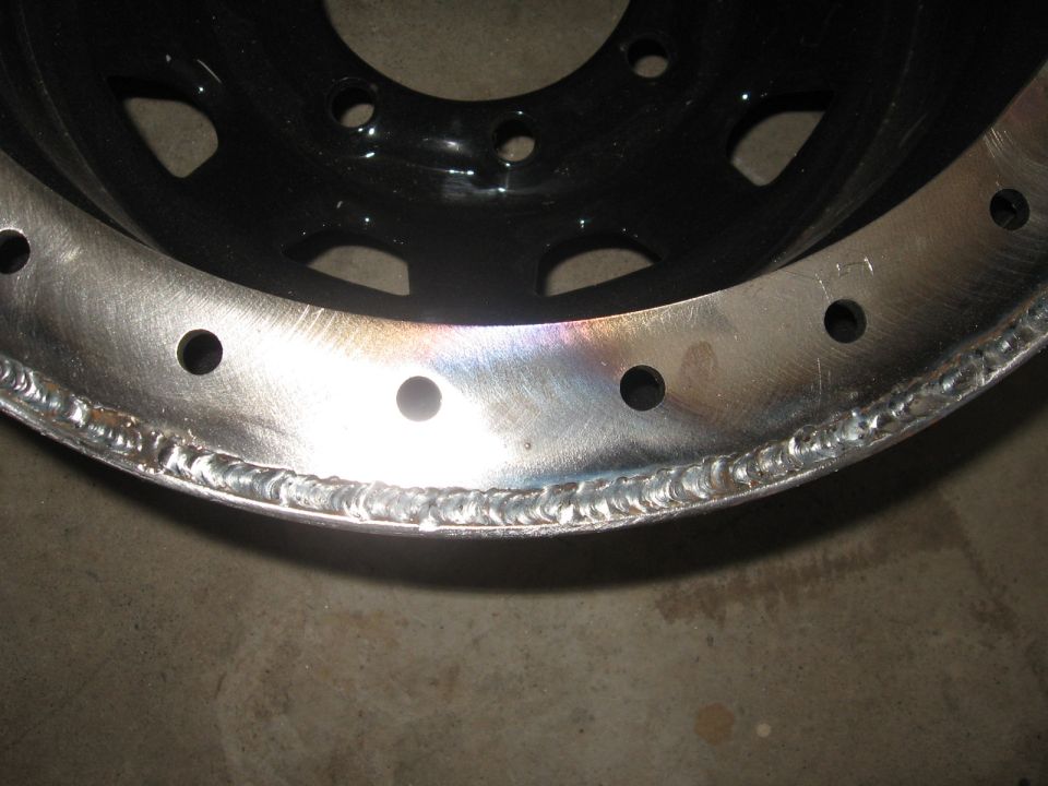 Close-up of a black and silver wheel rim with visible weld marks along the edge