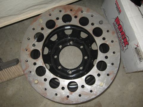 1979 Ford F-150 - A custom drilled brake rotor is shown with a black wheel. A box with 'Rock Crawler' branding is visible in the background.