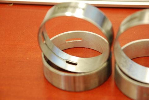 1996 Ford Bronco - Several metal engine bearings are shown on a textured orange surface.