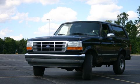 1995 Ford Bronco - This black 1995 Ford Bronco is shown from a 3/4 front angle, highlighting its distinctive grille.