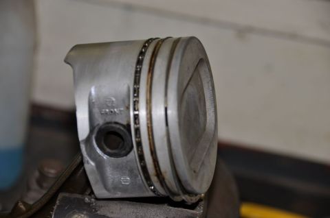 1996 Ford Bronco - A single piston, marked 'FRONT', is clamped in a vise, showing its oil rings.