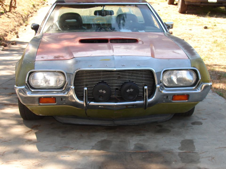 Front view of a customized pickup truck with a scoop on the hood and two round lights on the grille