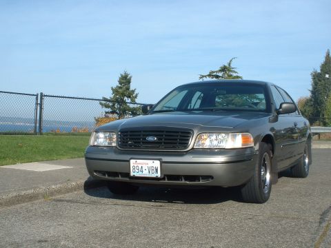 2000 Ford Crown Victoria - A 2000 Ford Crown Victoria is parked curbside on a sunny day with a clear blue sky.