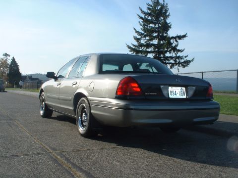 2000 Ford Crown Victoria - A gray 2000 Ford Crown Victoria sedan is viewed from the rear quarter angle on a sunny day.