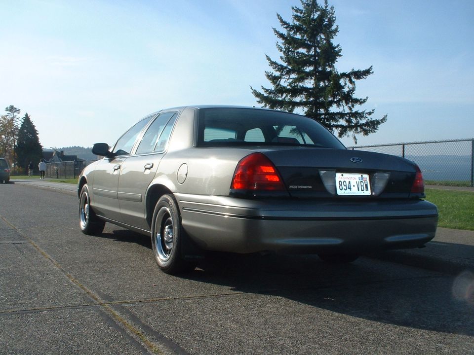 Gray 2000 Ford Crown Victoria sedan parked on a street, rear 3/4 view