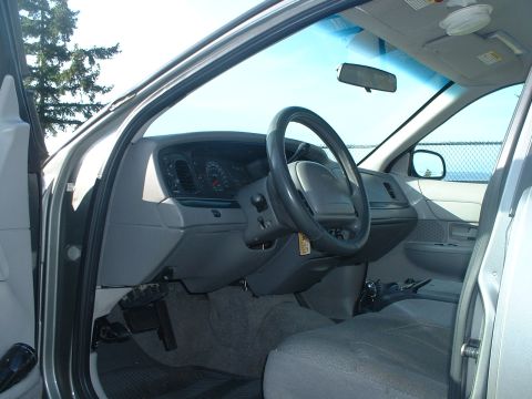 2000 Ford Crown Victoria - The interior of a 2000 Ford Crown Victoria, its dashboard, steering wheel, and passenger seat.