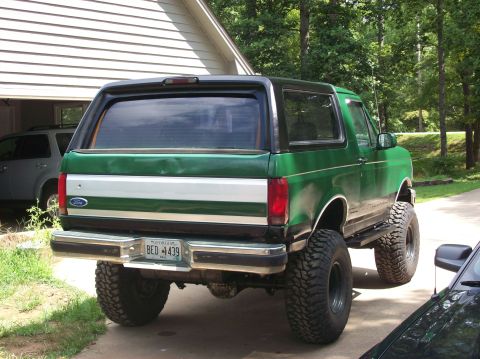 1992 Ford Bronco - Rear view of a lifted 1992 Ford Bronco with a green and silver two-tone paint job.