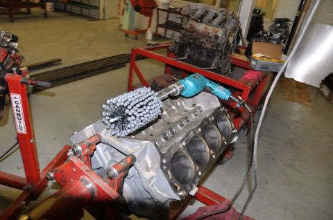 1996 Ford Bronco - A cylinder hone tool is used on an engine block mounted on a stand in a workshop.