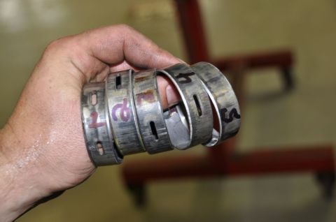 1996 Ford Bronco - A hand holds several metal cam bearings, each marked with a number.