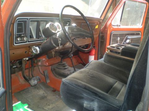 1979 Ford Bronco - The interior of this 1979 Ford Bronco features a brown dashboard, aftermarket gauges, and a bench seat.