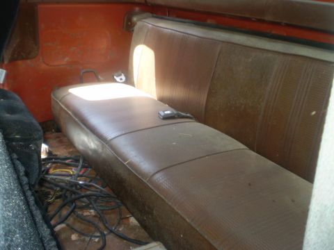1979 Ford Bronco - Vehicle interior with bench seat and exposed wiring on the floor.