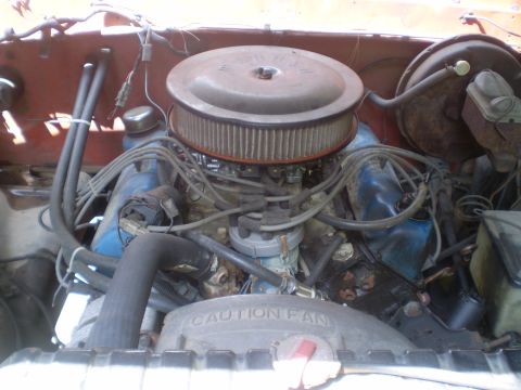 1979 Ford Bronco - The engine bay of a 1979 Ford Bronco is visible, its V8 engine components and a 'CAUTION FAN' warning.