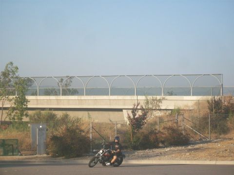 1985 Honda CMX250 Rebel - A motorcycle rider travels alongside a highway overpass on a clear day.