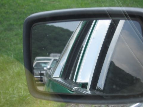 1991 Ford Crown Victoria - Reflection in the side mirror shows the chrome trim of a green car's side window and other vehicles in the background.