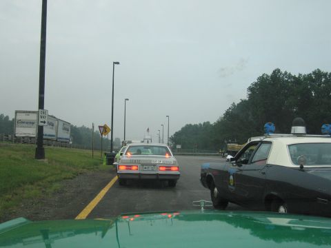 1991 Ford Crown Victoria - Two police cars are stopped in traffic on a cloudy day, one marked 'STATE OUT OF SERVICE'.