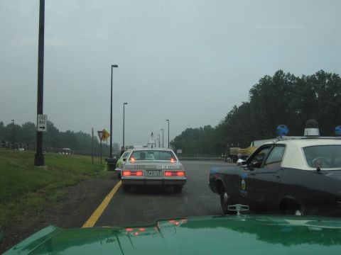 1991 Ford Crown Victoria - A police car with blue lights and a white roof is parked on the side of the road.