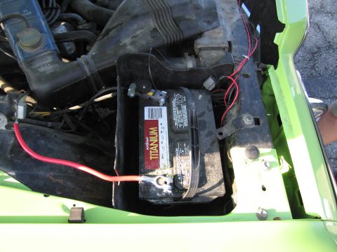 1991 Ford Crown Victoria - Close-up view of a car battery and engine components in a green vehicle's engine bay.