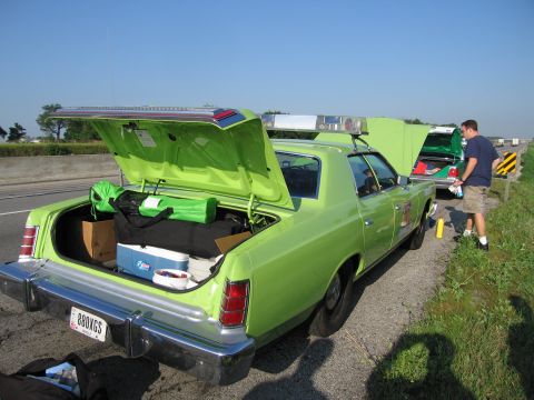 1991 Ford Crown Victoria - Two lime green sedans are parked on the shoulder of a highway, with their trunks and hoods open.
