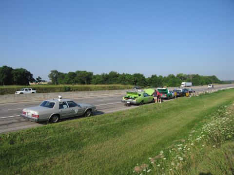 1991 Ford Crown Victoria - Multiple vehicles stopped on the side of a highway under a clear blue sky.