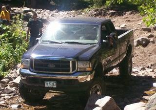 1978 Ford Bronco - A blue Ford F-250 pickup truck navigates a rocky trail.