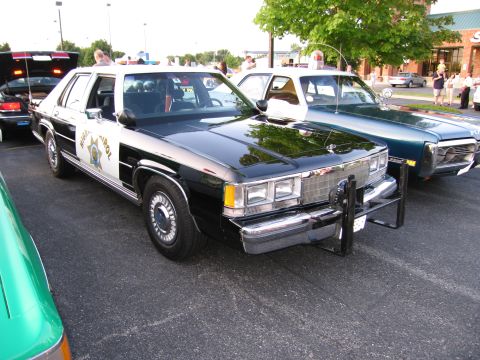 1991 Ford Crown Victoria - A black and white police car, likely a 1991 Ford Crown Victoria, is parked next to another vehicle.