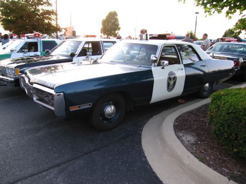 1991 Ford Crown Victoria - Multiple police cars are parked in a lot, one in the foreground with a two-tone paint scheme.
