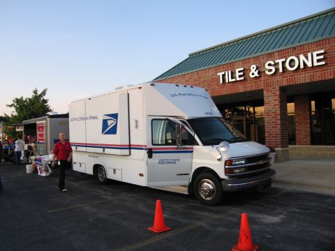 1991 Ford Crown Victoria - A white United States Postal Service truck is parked in front of a business with a man standing nearby.