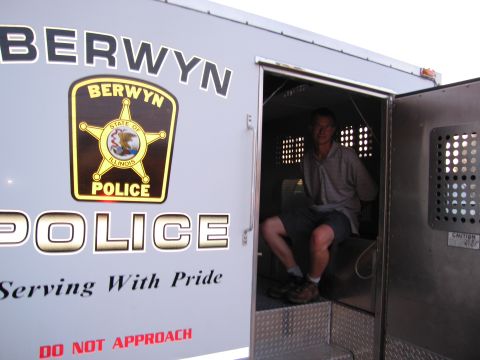 1991 Ford Crown Victoria - A man is seated inside a Berwyn Police van, which has 'Serving With Pride' written on its exterior.