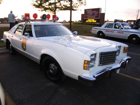 1991 Ford Crown Victoria - A white police car with a light bar and siren is parked next to another police car that reads "Wood Dale Police".