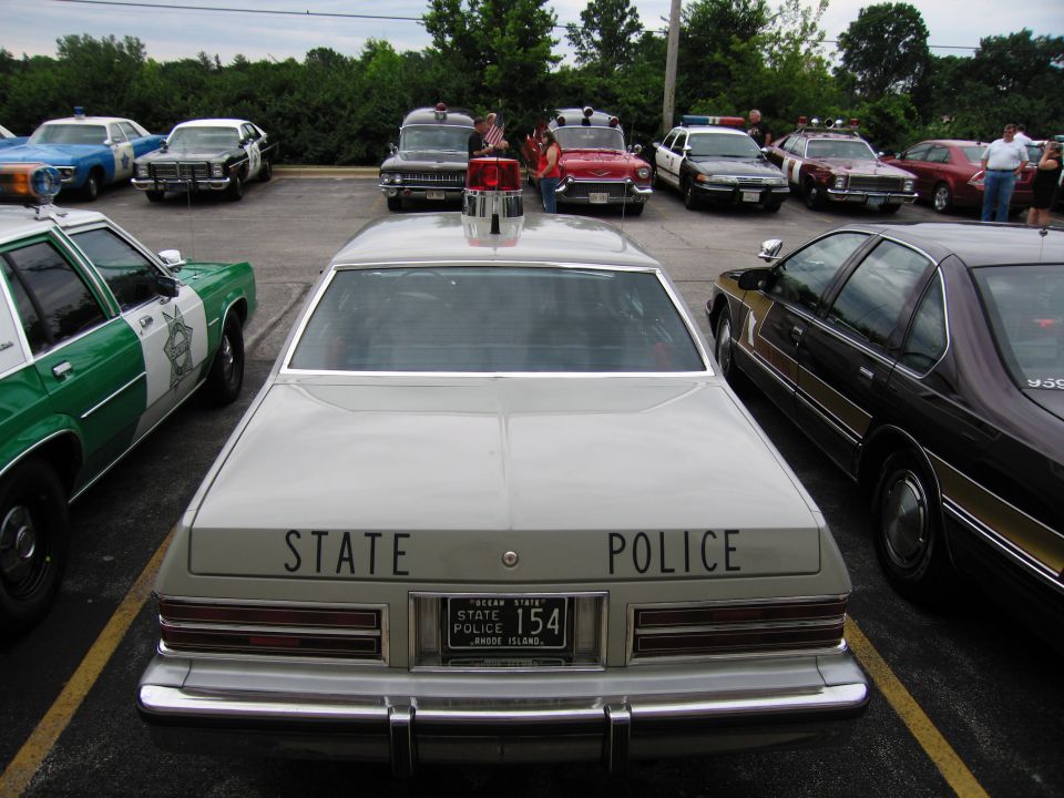 Rear of a tan STATE POLICE sedan, Rhode Island plate 154, with single roof light