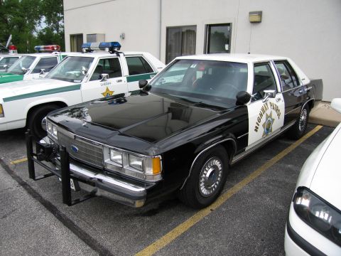 1991 Ford Crown Victoria - A 1991 Ford Crown Victoria police car is parked next to other patrol vehicles.