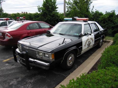 1991 Ford Crown Victoria - A 1991 Ford Crown Victoria police car is parked in a lot next to another vehicle.