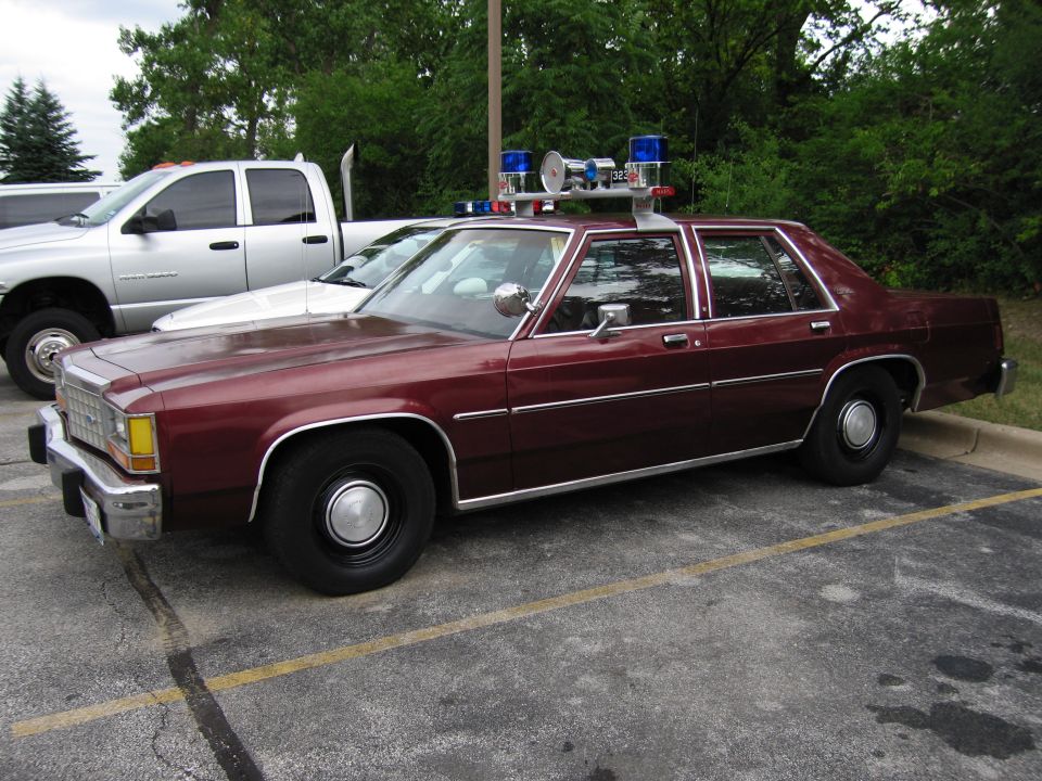 Maroon Ford LTD Crown Victoria police sedan with roof light cluster