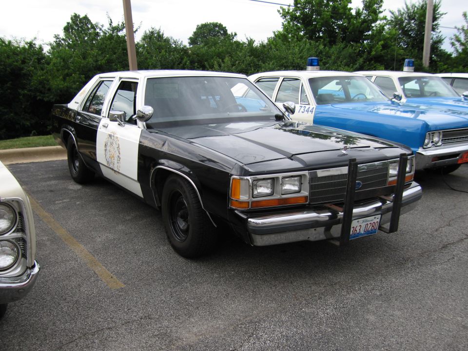 Black and white Canine Patrol Ford sedan with push bar in lot