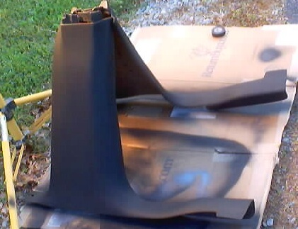 1999 Ford Taurus - Black plastic interior pillar or kick trim panel laid on cardboard on the ground.