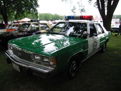 1991 Ford Crown Victoria - A 1991 Ford Crown Victoria police car is seen at an outdoor event with other vehicles.