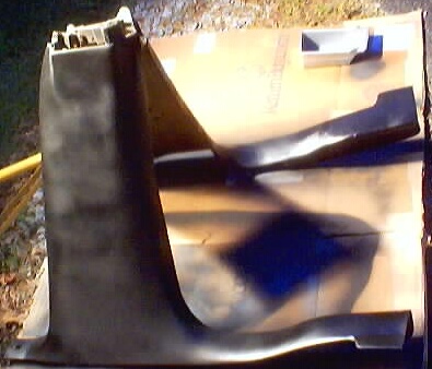 1999 Ford Taurus - Two black plastic interior trim pieces are laid out on a piece of cardboard, possibly for painting or repair.