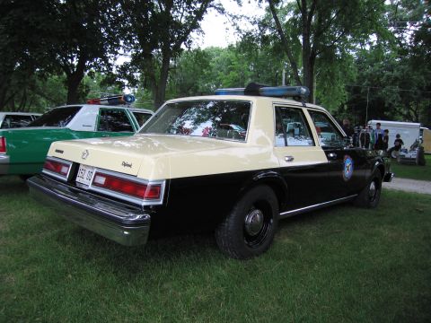 1991 Ford Crown Victoria - A two-tone police car is parked on grass next to another police car.