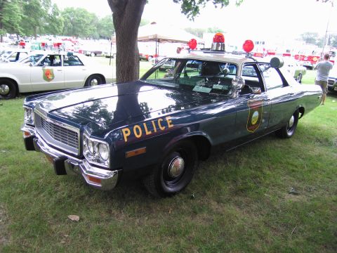 1991 Ford Crown Victoria - A vintage police car with red lights on the roof is parked on a grassy field.