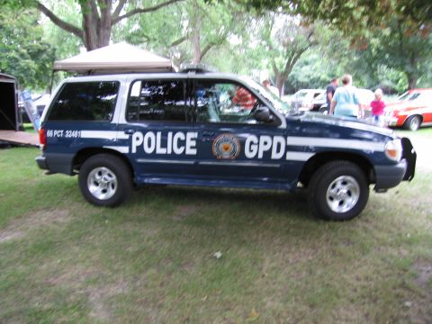 1991 Ford Crown Victoria - A police SUV is parked on a grassy area with trees in the background.
