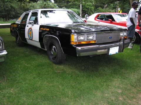 1991 Ford Crown Victoria - This 1991 Ford Crown Victoria police car is parked on grass next to another vehicle.