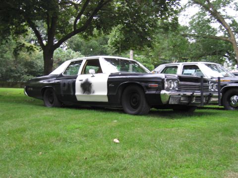 1991 Ford Crown Victoria - Two police cars are parked on a grassy area, with one in the foreground showing a black and white paint scheme.
