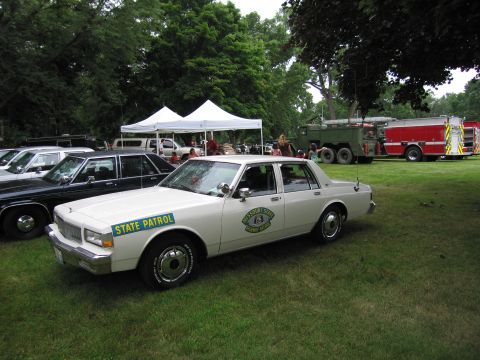 1991 Ford Crown Victoria - A white Missouri State Highway Patrol sedan is parked on a grassy field next to other vehicles and tents.