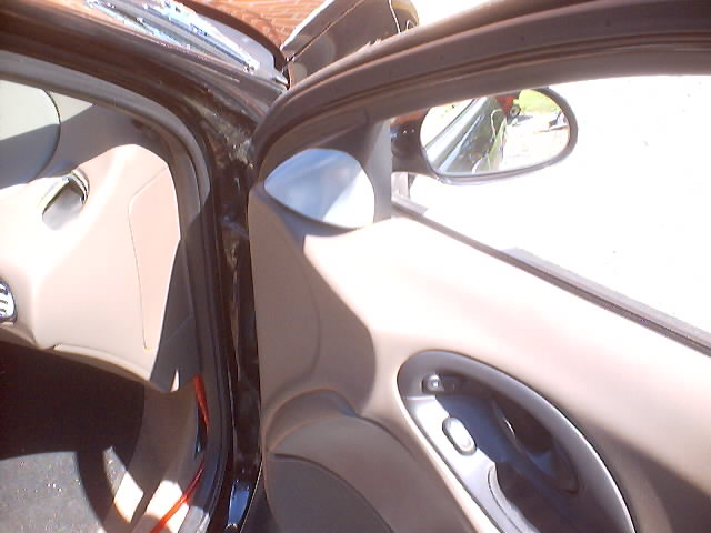 Interior door panel with tan trim and silver handle, side mirror visible