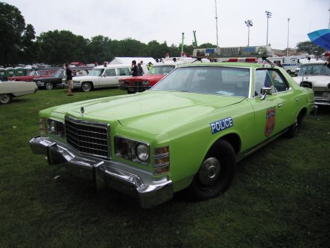 1991 Ford Crown Victoria - This lime green police car is parked on a grassy field with other vehicles in the background.