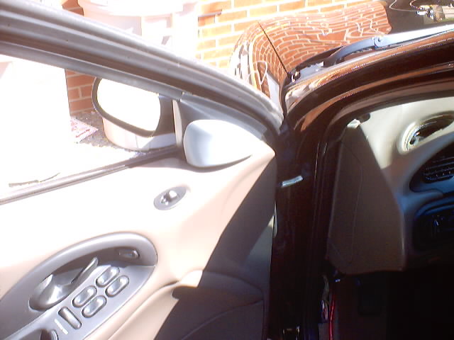 Car door ajar showing interior door panel with power window switches and side mirror