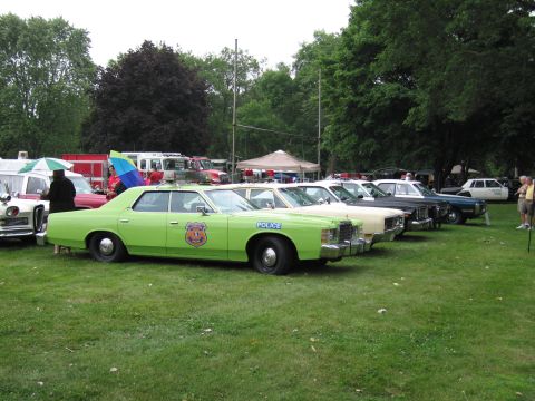 1991 Ford Crown Victoria - A lineup of older police cruisers displayed outdoors on a grassy field.