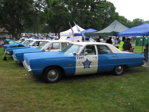 1991 Ford Crown Victoria - A line of vintage police cars, including one with 'Chicago Police' markings, are displayed outdoors under tents.